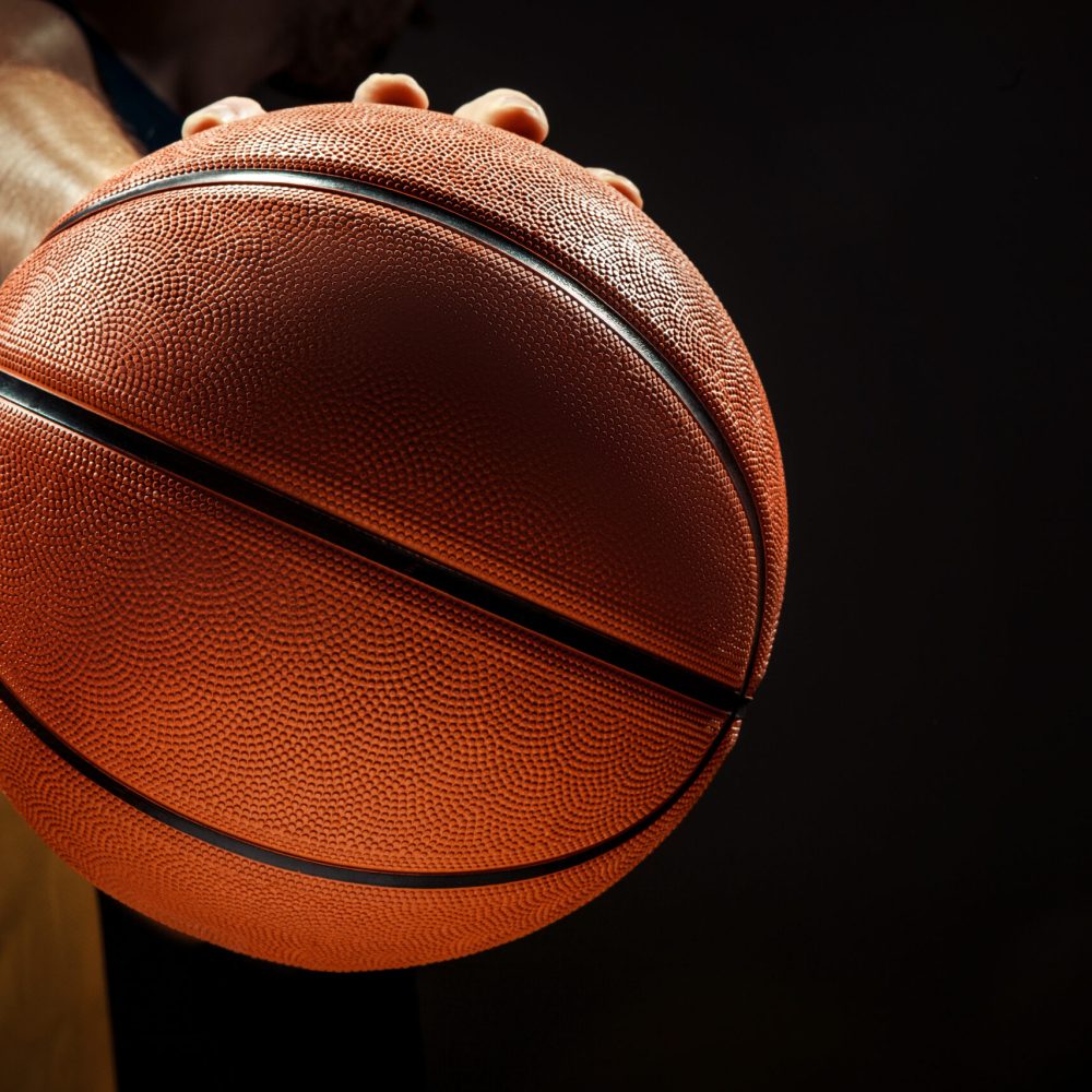 Silhouette view of a basketball player holding basket ball on black background